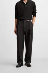 Pantalón negro de corte amplio, con pliegues en la parte delantera, bolsillos laterales y traseros de ojal.