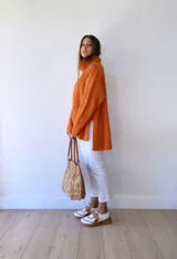 Zapatillas deportivas blancas con detalles en cuero color salmón y suela gruesa con detalles en naranja.