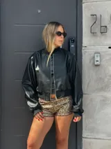 Campera bomber de cuero sintético color negro, con cuello mao, cierre frontal y puños y cintura elastizados.