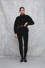 Pantalón de pana negro, corte slim, con cintura alta y cierre frontal con botón y cremallera.