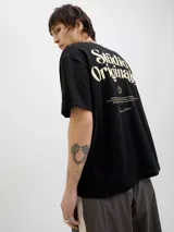 Remera negra de manga corta y cuello redondo con estampado en la espalda con la frase "Studio Originals" en color crema.