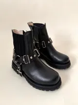 Botín negro de cuero vacuno con elásticos laterales y estribo desmontable con apliques y herrajes metálicos color níquel.