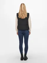 Chaleco negro acolchado con cuello alto y cierre frontal con cremallera. Tiene bolsillos laterales y diseño sin mangas.
