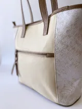 Bolso tipo tote bag color beige con laterales estampados y detalles en cuero marrón.