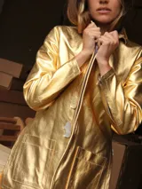 Blazer de cuero color fucsia con aberturas laterales y aplique tipo pin desplegable bañado en bronce, complementado con botones de nácar.