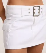 Minifalda blanca de sarga con cintura baja, trabillas, bolsillos cargo y cinturón con hebilla cuadrada metálica.