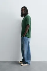 Camiseta verde oscuro de corte relaxed fit, cuello redondo, manga corta y bolsillo plastrón en el pecho.