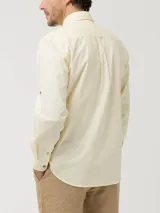 Camisa manga larga color amarillo pastel, confeccionada en popelina de algodón orgánico, con botones de madera, bolsillo en el pecho y protección UPF +20.