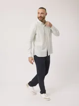 Camisa de hombre de manga larga con rayas verticales en tonos verde claro y blanco. Confeccionada en una mezcla de lino y algodón, presenta cuello abotonado y bolsillo en el pecho.