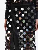 Pollera cruzada de largo midi, confeccionada en guipur negro con espejos circulares bordados. Presenta un lazo de ajuste en la cintura y forrería interna al tono.