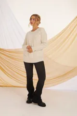 Buzo de tejido suave en tonos beige y crudo, con diseño holgado y cuello redondo.