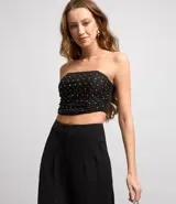 Blusa cropped con escote strapless, confeccionada en tul metalizado con brillos aplicados y cierre track.