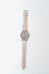 Reloj analógico con caja redonda y correa de cuero sintético color rosado pálido. La esfera es gris claro con números romanos en relieve y manecillas oscuras.
