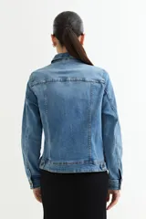 Chaqueta de jean celeste con apliques de strass en cuello y hombros, corte clásico, mangas largas y bolsillos frontales.