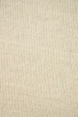 Poncho color crema de tejido de punto industrial con cuello alto y aberturas laterales para los brazos.