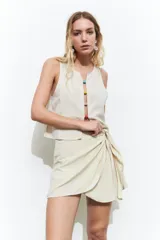 Minifalda color beige con diseño cruzado y nudo lateral.