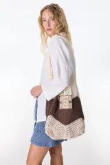 Bolso tejido color crudo con base negra y parche característico de "The Flowers Club".