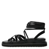 Sandalia negra con tiras para atar, de diseño moderno y suela plana.