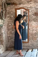 Vestido largo azul marino de lycra de algodón, con corte amplio, escote redondo al frente y escote profundo en la espalda. Tiene breteles con lazos ajustables, bolsillos y tajos laterales.