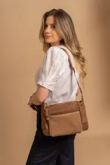 Bandolera de diseño moderno, color beige rosado, con correa regulable y bolsillo frontal con cierre.