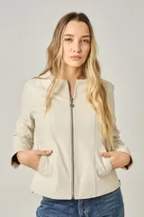 Campera de cuero color natural, con cuello redondo, cierre frontal con cremallera y bolsillos laterales con cierre. Diseño clásico y corte entallado.