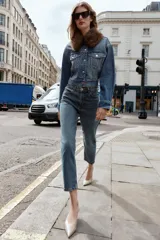 Pantalón de jean azul de tiro alto, corte mom fit, tobillero y con cinco bolsillos. Cierre frontal con cremallera y botón.