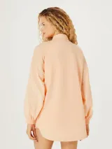 Camisa naranja de corte oversize con cuello camisero y mangas largas.