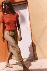 Top corto de punto color naranja, con cuello redondo amplio y manga corta.