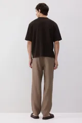 Pantalón marrón claro de lino, corte recto, con cintura elástica y cordón ajustable. Posee bolsillos laterales y trasero.