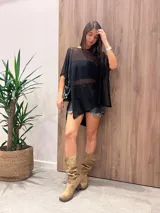 Poncho de punto grueso, color beige, con cuello redondo y diseño estampado en tonos tierra y negro.