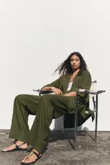 Pantalón color beige de lino, de tiro alto con cintura elástica, bolsillos laterales ocultos en costura y pernera ancha.