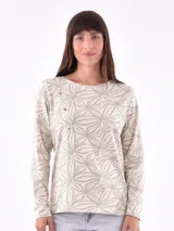 Remera de manga larga color beige con estampado abstracto en tonos grises y detalle de botones dorados en el hombro.