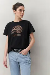 Remera blanca de manga corta con estampado de una concha marina y la frase "ocean breeze, mind at ease" en color marrón.
