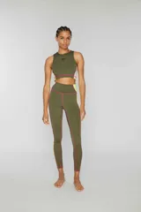Crop top deportivo sin mangas de lycra color verde militar, con banda lateral color block en amarillo y rosa, pespuntes overlock en contraste y logo estampado en el frente.