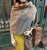 Pashmina rectangular con estampado de figuras geométricas y animales en tonos marrón, naranja y gris.