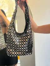 Cartera negra tipo hobo con tachas plateadas.