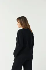 Sweater negro de punto suave con cuello redondo y hombros caídos.