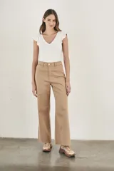 Pantalón wide leg color beige, de tiro alto, ligeramente ajustado en cintura y con ruedo desflecado.