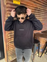 Canguro negro de algodón con capucha, corte oversize y bolsillo tipo canguro. Estampa bordada en el pecho con la palabra "BOHEMIANDESIGN".