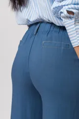 Conjunto de camisa de manga corta con cuello y pantalón de corte recto, ambos de tela simil lino color beige con bordados blancos.