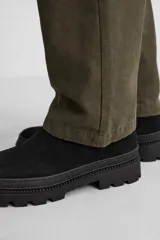 Bota Chelsea negra de cuero con acabado serraje, caña baja, puntera redondeada, tirador trasero y suela track con volumen.
