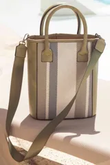 Matera azul marino con diseño frontal en telar rayado en tonos azules, blancos y amarillos. Cuenta con doble asa de mano y correa de hombro ajustable.