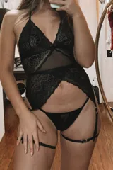 Conjunto de lencería negro de encaje y microtul, compuesto por un body tipo basque con portaligas incorporado y una tanga colaless regulable. No incluye medias.