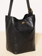 Cartera tipo tote confeccionada en cuero vacuno color crudo, con textura tipo piel de cocodrilo. Tiene correa larga al hombro y apliques metálicos con el logo de la marca. Incluye sobre interno desmontable con cierre.