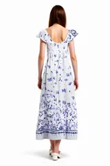 Vestido midi blanco con estampado floral azul, corte amplio, cuello redondo con volados y mangas cortas con volados.