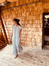 Vestido tejido color gris con hilado levemente brillante, corte oversized y flecos en el ruedo.