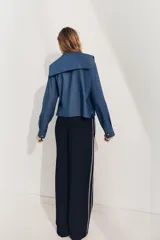 Camisa celeste de algodón con efecto denim, cuello bobo, escote pico, manga larga con puños y cierre frontal con botones.