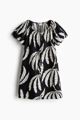 Vestido corto evasé de algodón con estampado de hojas color blanco sobre fondo negro. Tiene mangas globo cortas de diseño raglán y escote redondo con cordón para ajustar.