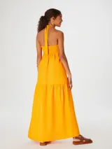 Vestido largo naranja con escote halter y detalle de nudo en el pecho.