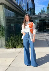 Camisa blanca traslúcida con botones y estampado de flores anaranjadas.